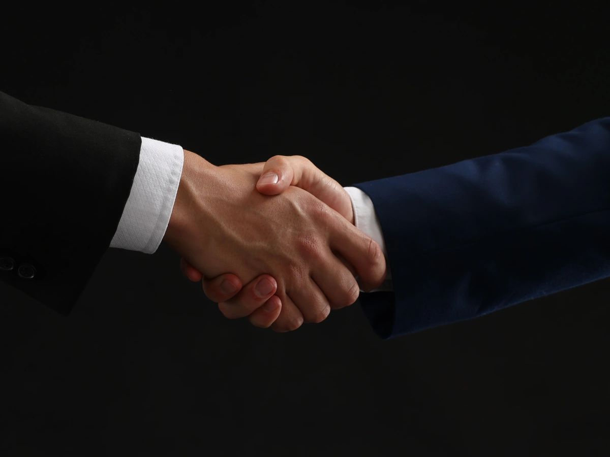 Sales leaders shaking hands in a modern corporate office
